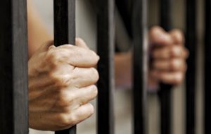 Manos en barras de la cárcel tras una condena de CRS 18-7-206