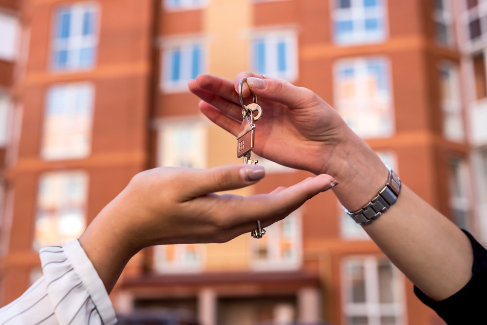 A person handing keys to an apartment to another.
