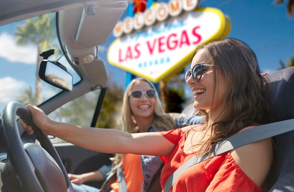 A woman smiling as she drives past the Las Vegas sign.