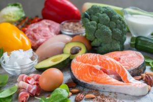 A spread of various low-carb foods, such as salmon and eggs, laid out on a table.