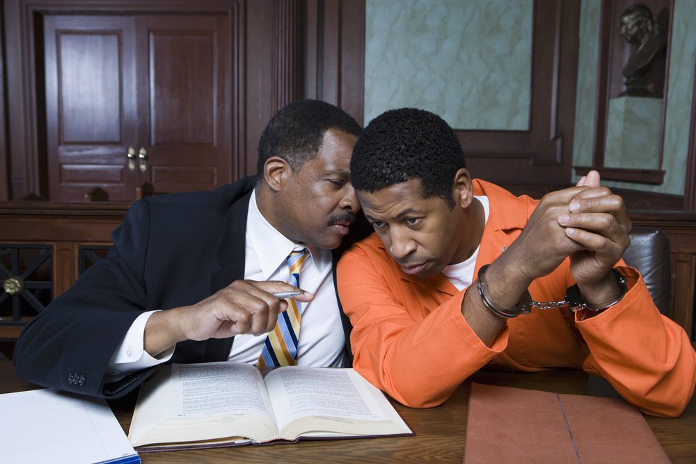 A defense attorney advising his client in court.
