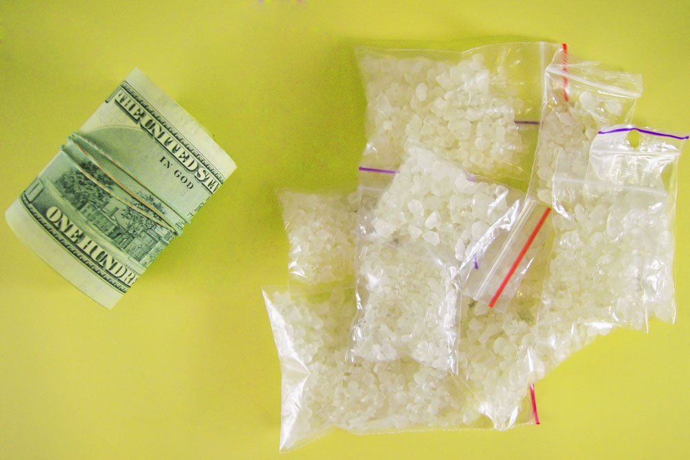 Bags of PCP crystals next to a roll of money.