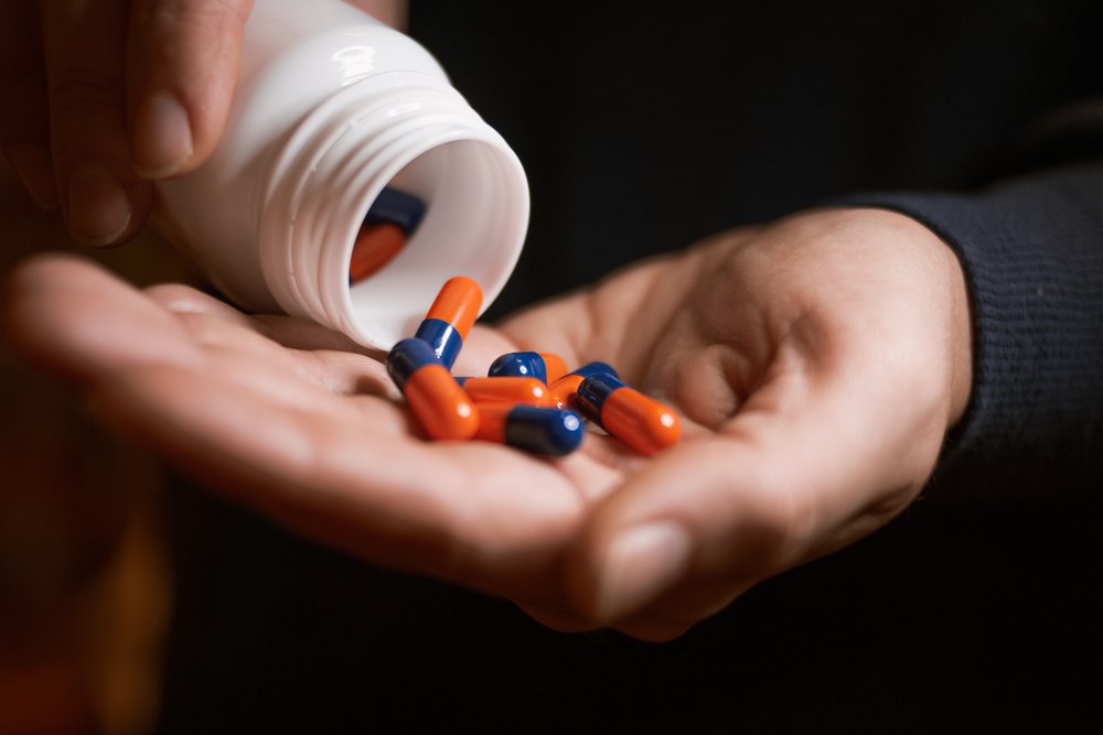 Pills being poured out of a bottle into a hand.