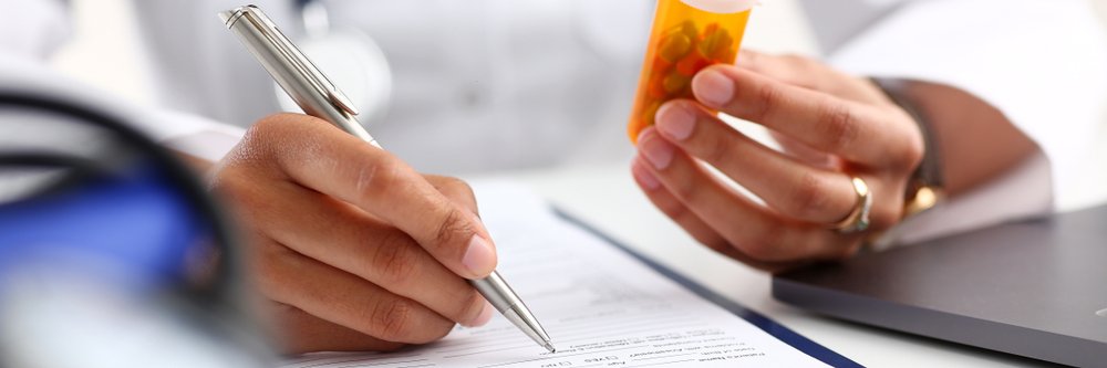 A man in a lab coat writing a prescription.