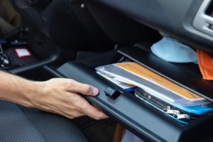 Driver's hand opening glove box to get registration out