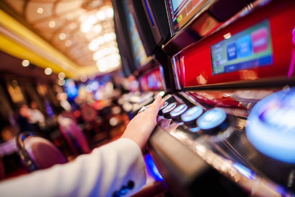 A person tapping on the slot machine buttons. Perhaps in an effort to manipulate the machine.