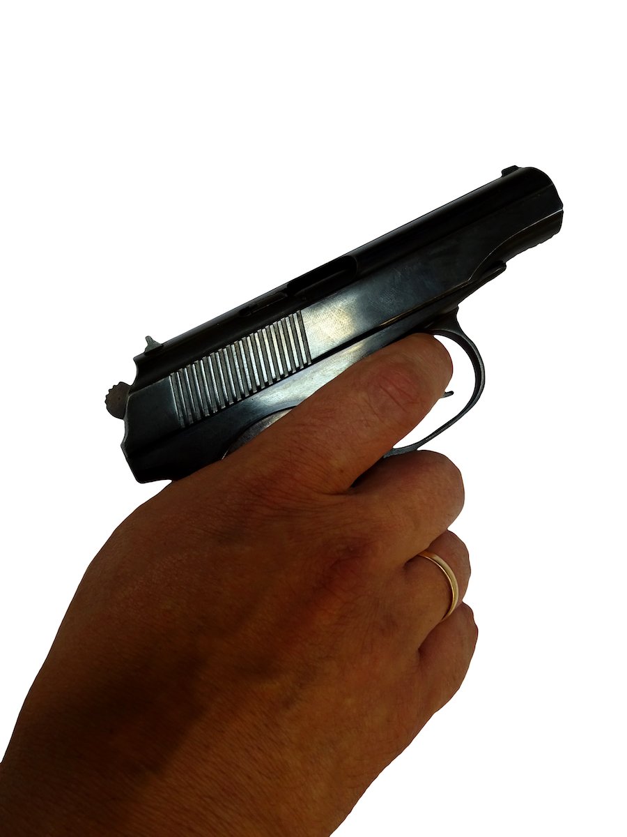 Hand with wedding ring holding pistol