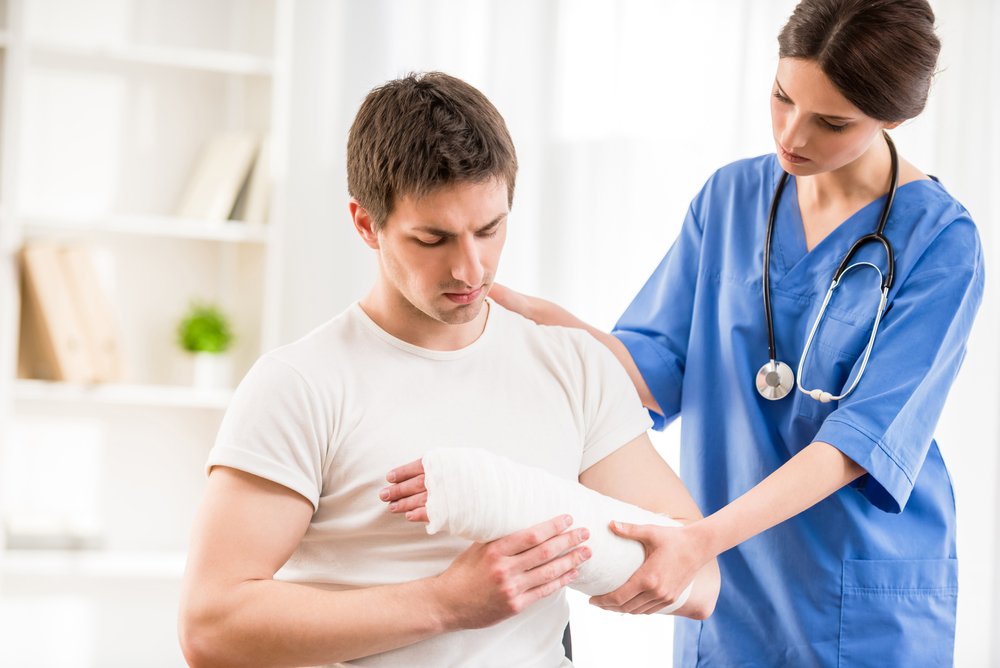 A young man having a cast put on him by a nurse after a work injury