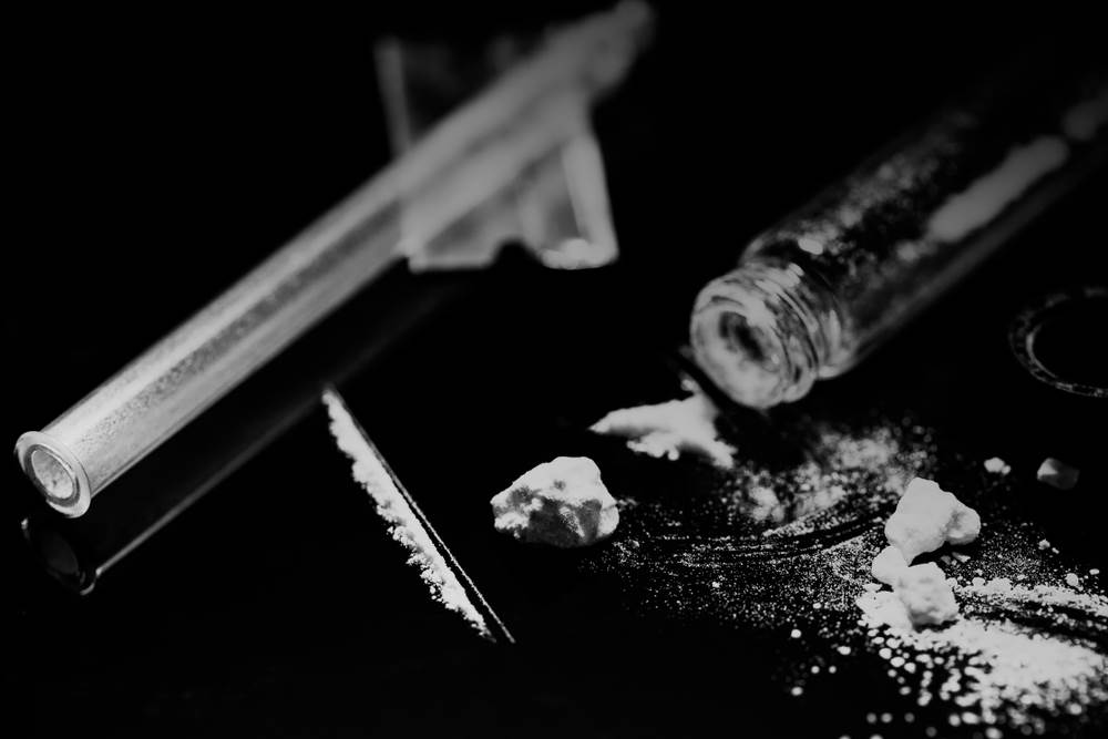 A line of cocaine next to a vial and a razor used to cut the line.