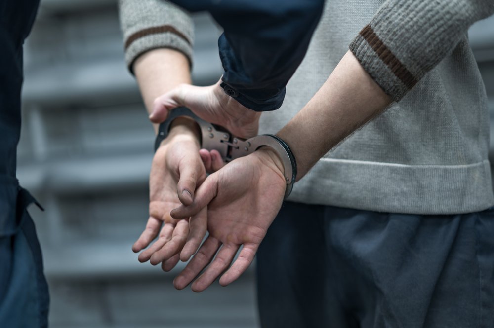A man in handcuffs after an arrest, possibly leading to an end to his possibilities of receiving spousal support.