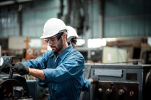 A factory worker working on a machining tool.