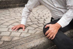 Man on ground after slipping on uneven pavement outside