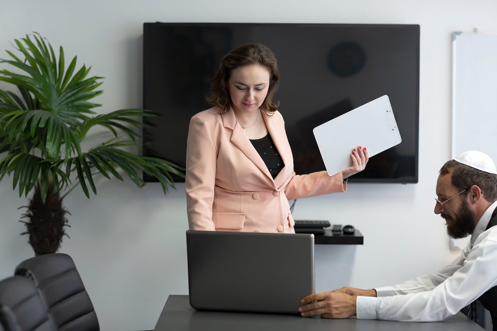 A man wearing a yarmulke in an office with a woman.