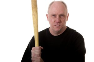 A man menacingly holding a bat while staring one down.