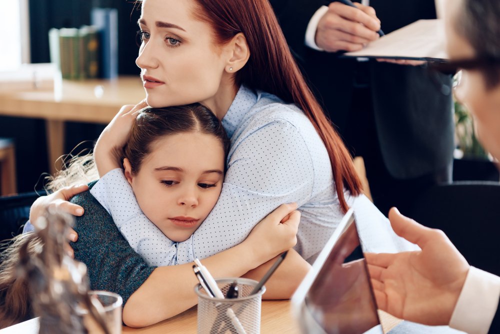 A mother holding her daughter close to her, to comfort her.