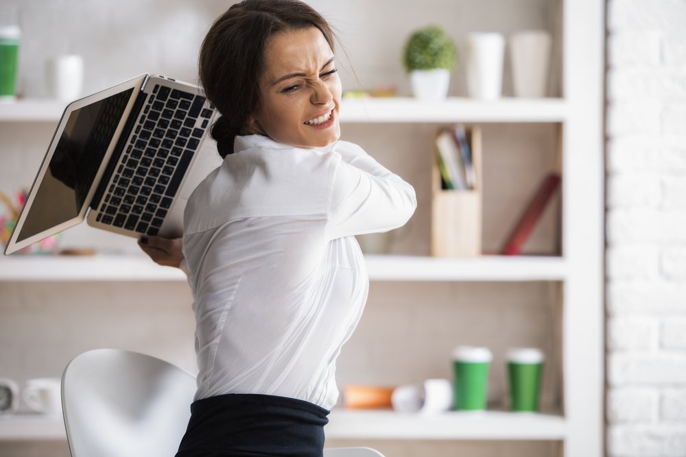 A furious office worker smashing her laptop.
