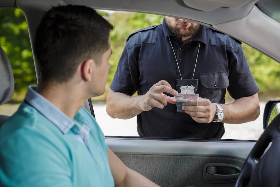 Un oficial de policía inspeccionando la licencia de conducir después de una parada de tránsito