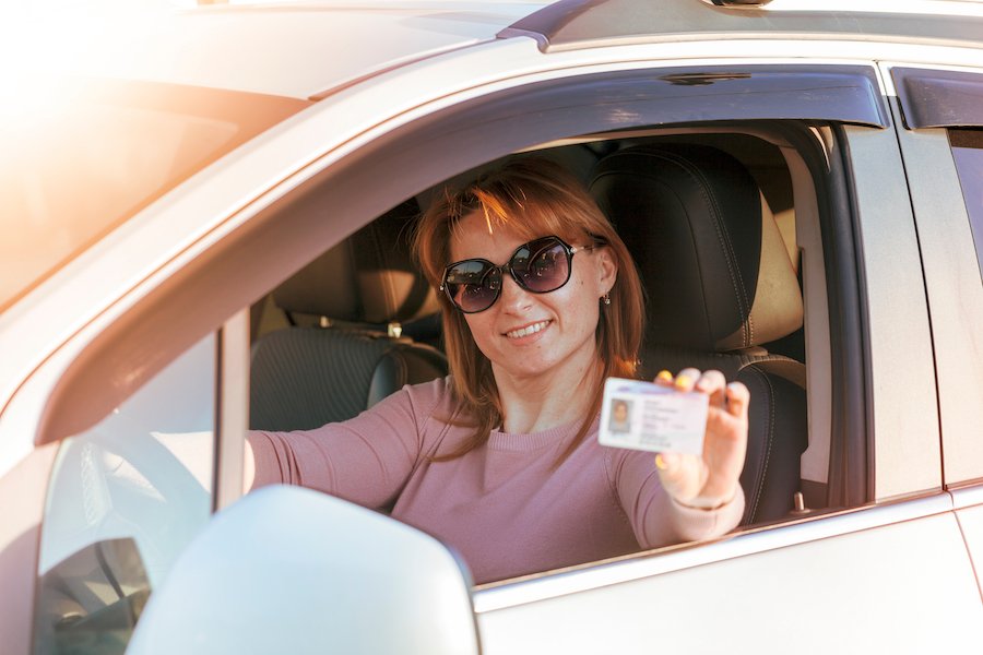 Woman in driver's seat holding her driver's license