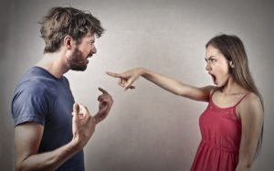 Una mujer señalando con el dedo a un hombre acusándolo (posiblemente de agresión sexual) contra un fondo gris Una mujer señalando con el dedo a un hombre acusándolo (posiblemente de agresión sexual) contra un fondo gris