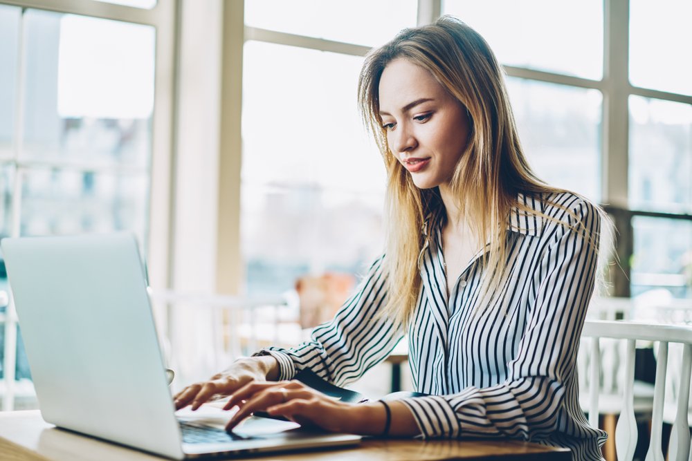 A young woman typing up a demand letter on her laptop.