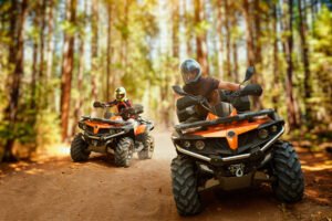 Two ATVs riding in a wooded area