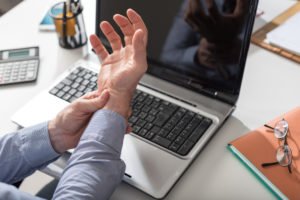 A man holding his wrist in pain due to carpal tunnel syndrome.