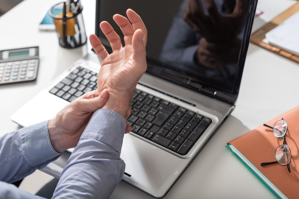 A man holding his wrist in pain due to carpal tunnel syndrome.