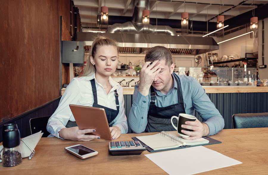Two business owners fretting over their finances in their restaurant