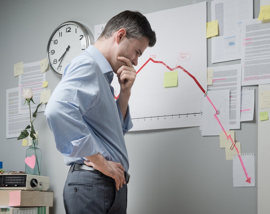 Businessman in office fretting over plummeting revenues.
