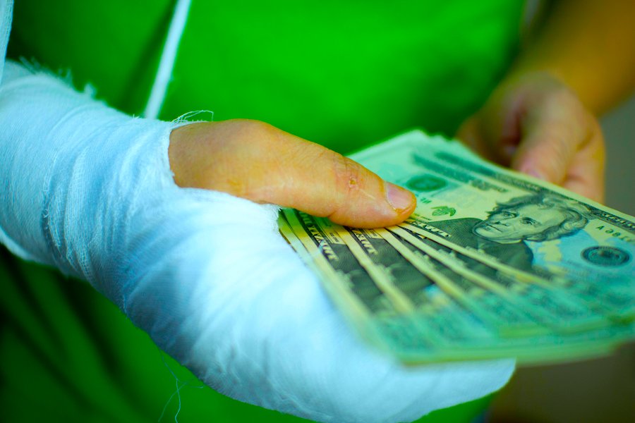 Injured worker with a cast holding cash to signify the extra money received for a late disability payment under LC 4650