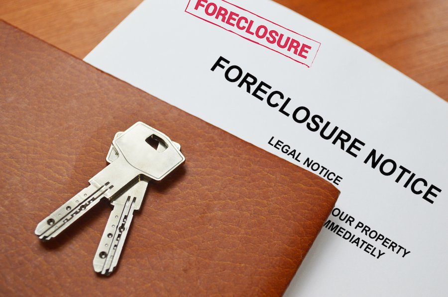 Paper that says "Foreclosure" notice with house keys