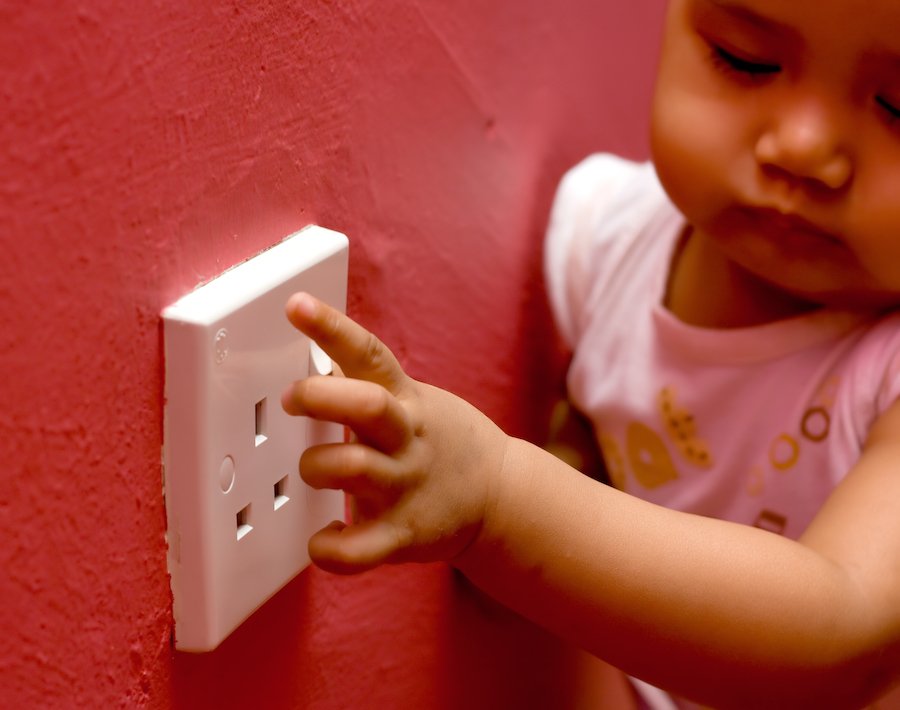 Niño tocando una toma eléctrica como ejemplo de peligro para los niños