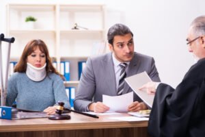 Víctima de compensación de trabajadores con collarín junto a abogado hablando con juez