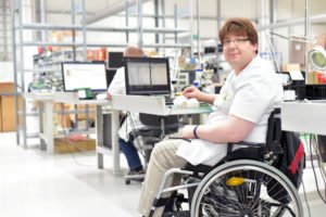 A man returning to work in a wheelchair after a workplace injury.