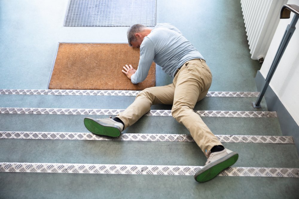 A man on the ground after falling due to his apartment's slippery stairs.
