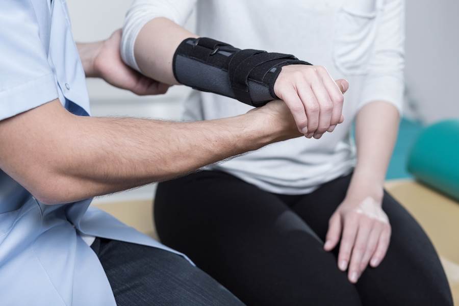 Fisioterapeuta ayudando a una mujer con el brazo roto