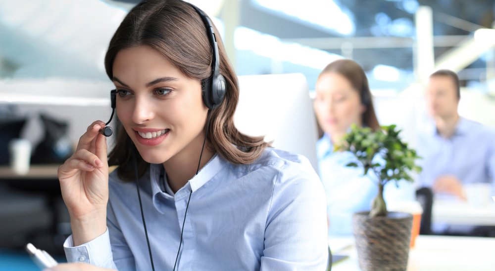 Una recepcionista atendiendo atentamente a la persona al teléfono.