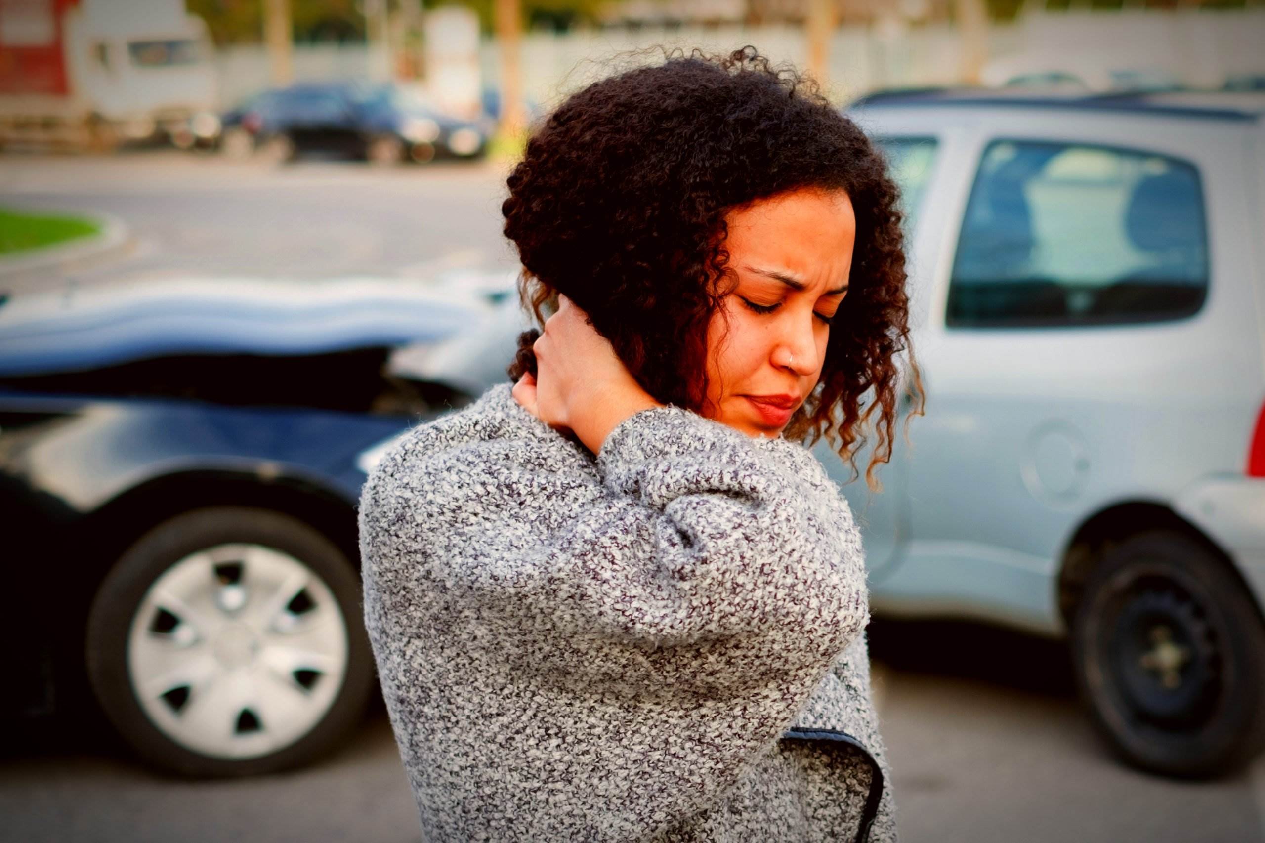 Una mujer sosteniendo su cuello con dolor después de un accidente automovilístico