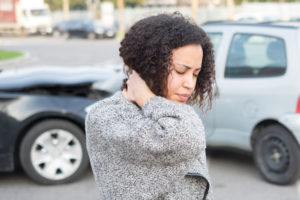 Mujer sosteniendo su cuello lesionado después de un choque de autos