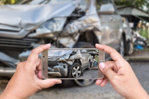 Hombre tomando foto del resultado de un accidente de automóvil en un teléfono inteligente