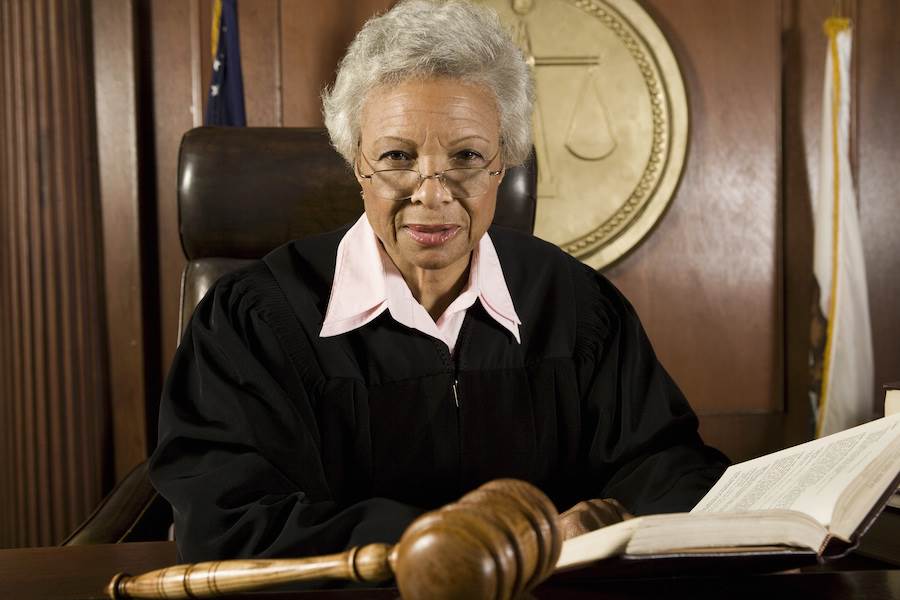 Senior judge sitting with book and gavel in courtroom