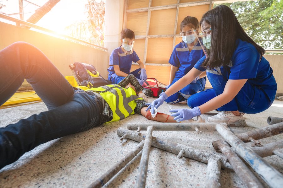 Tres paramédicos atendiendo a un trabajador de la construcción lesionado en el suelo
