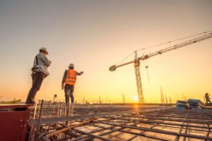 Dos trabajadores con grúa en el fondo