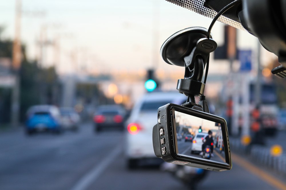 A dashcam on the interior of a a car's window shield.