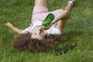 A girl inebriated while finishing off a bottle of wine at a public park.