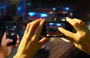 Onlookers filming police on their smartphones.