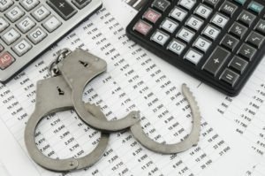Calculators, financial statements, and handcuffs