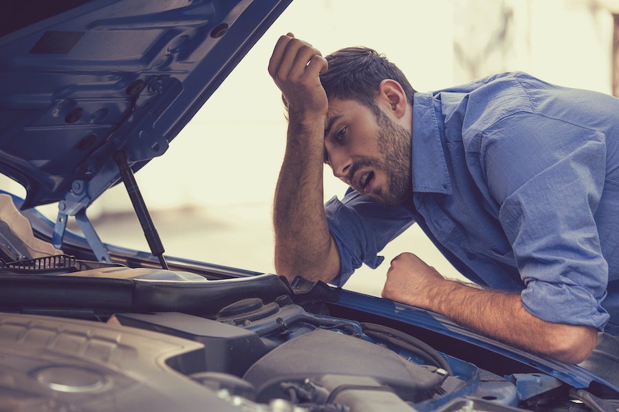 Hombre mirando debajo del capó de un automóvil limón