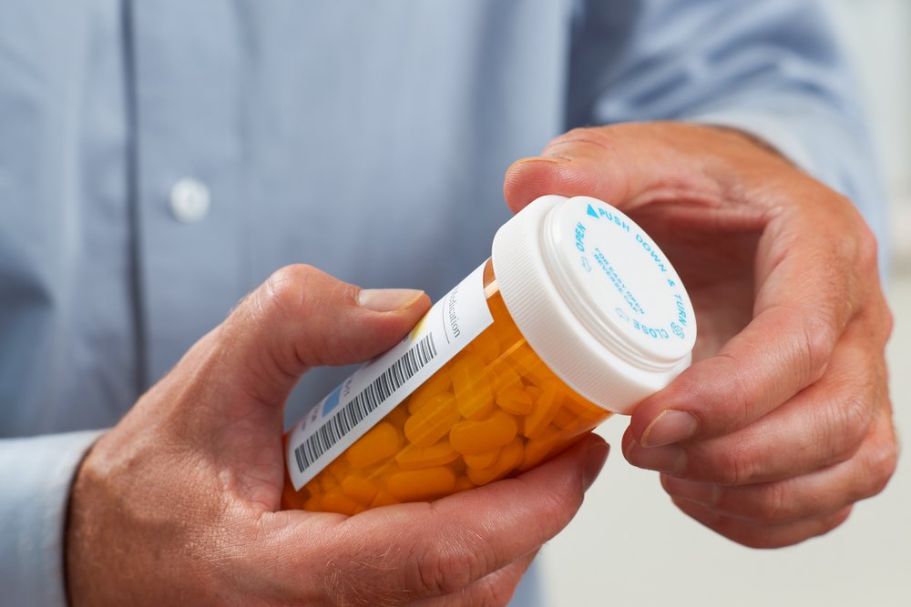 A man holding a bottle containing the medicine he was prescribed.