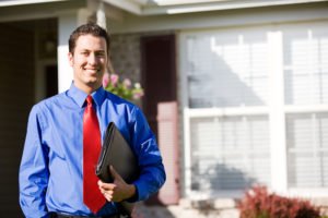 A licensed real estate agent smiling outside of a home.